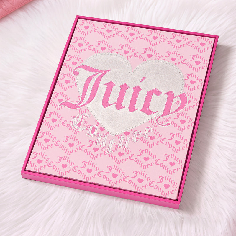 The Shadow Box Wall Art, 16″ x 20″, features a pink Juicy Couture box adorned with a glittery heart and decorative text, set on a white fluffy surface—creating the perfect fashion-inspired accent for any space.