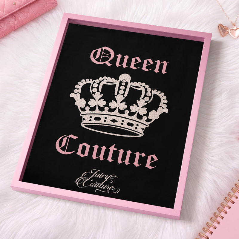 The 18″ x 24″ Shadow Box Wall Art features a black framed sign adorned with a jeweled crown and the words “Queen Couture” and “Juicy Couture” in pink font, styled atop a white fur surface with nearby pink accessories, for a chic, fashion-inspired display.