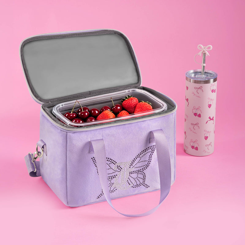 The Chill Couture Cooler Bag, featuring a stylish lavender hue and butterfly design, holds fresh strawberries and cherries. Beside it sits a pink tumbler adorned with butterflies and topped with a bow-shaped straw, all set against a pink background—perfect for those seeking both charm and function in their insulated cooler bag.