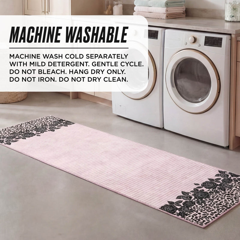 A Finely Washable Rug, 2' x 6', with a pink and black floral Juicy Couture design sits in front of a washer and dryer. Text overlay: machine wash cold, gentle cycle, do not bleach, iron or dry clean, hang dry only.