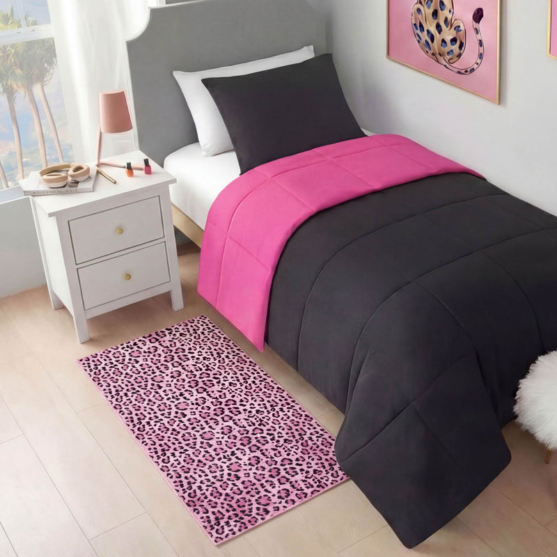 A neatly made bed with black and bright pink bedding sits beside a white nightstand topped with a lamp and makeup items. A Finely Washable Rug, 2' x 4', in pink leopard print covers the light wood floor. Leopard wall art hangs above the bed.