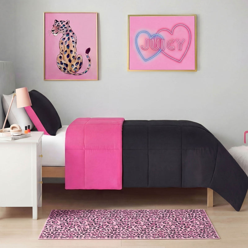 A neatly made bed with black and hot pink bedding sits beside a white nightstand. Above are two framed art pieces—a leopard illustration and pink neon JUICY hearts. On the floor is the Finely Washable Rug, 2' x 4', in pink leopard print.