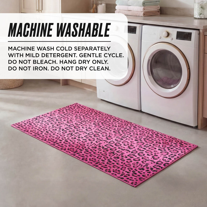 A Finely Washable Rug, 2' x 4', with a pink leopard print and non-skid backing is placed in front of a washer and dryer. A text box gives care instructions: machine wash with cool water and mild detergent.