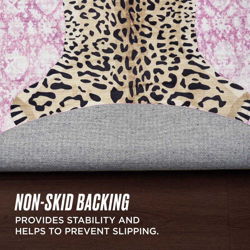 A Finely Washable Round Rug with a leopard print design is partly lifted on a wooden floor, showing its non-skid backing for stability and slip prevention.