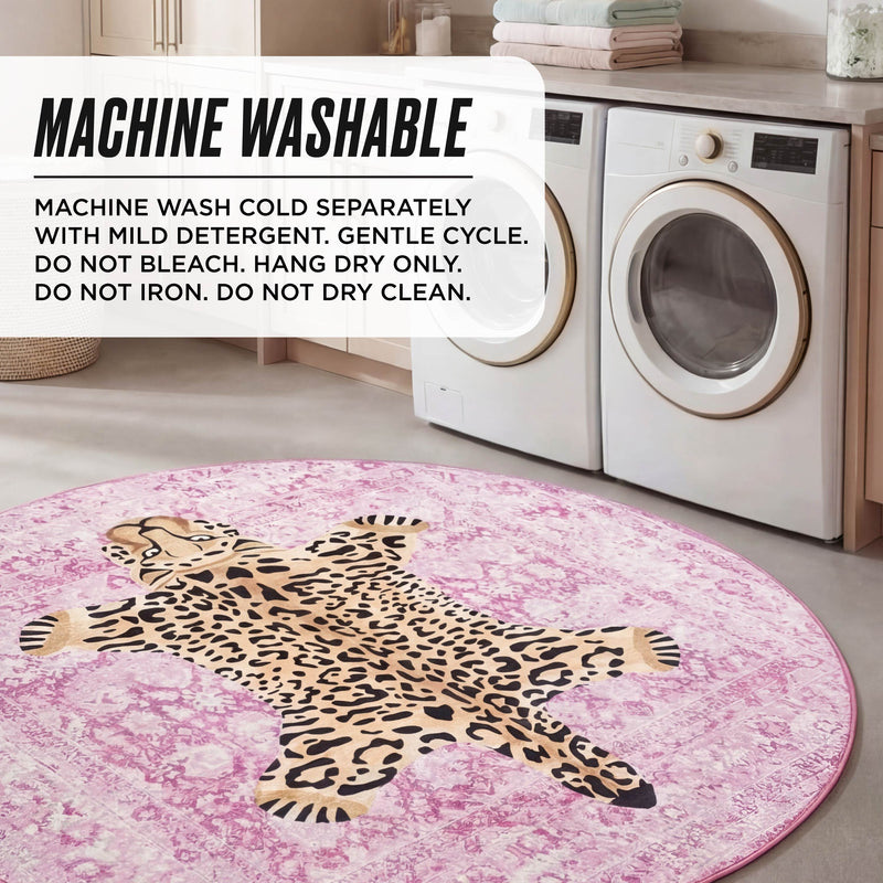 A laundry room with a washing machine and dryer features the Finely Washable Round Rug, a pink rug with a cartoon leopard design and non-skid backing. Text overlay gives machine washing instructions for the rug.