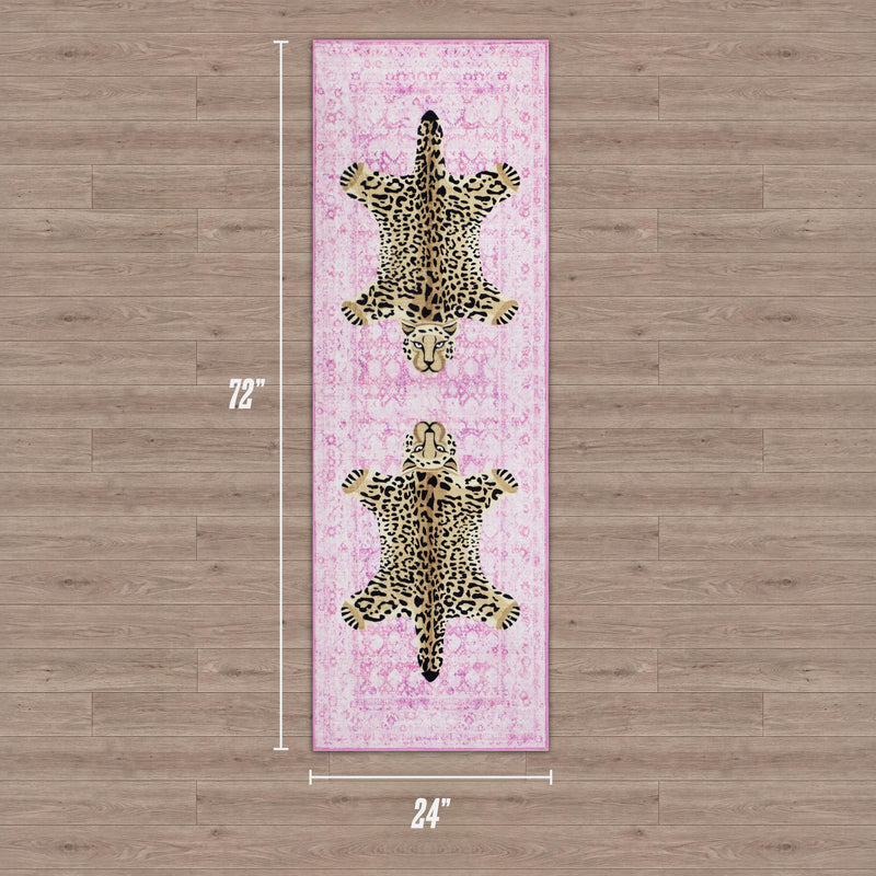 The Finely Washable Rug, 2' x 6', features an ultra-soft pink surface with two illustrated leopards head-to-head along its length, adding style to a wooden floor. This rug is machine-washable for easy care.