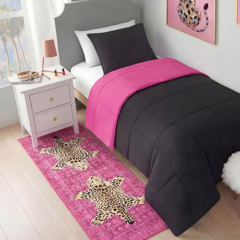 A neatly made bed with black and hot pink bedding stands next to a white nightstand. A Finely Washable Rug, 2' x 6', lies on the floor, and a framed leopard artwork hangs on the wall above the bed.