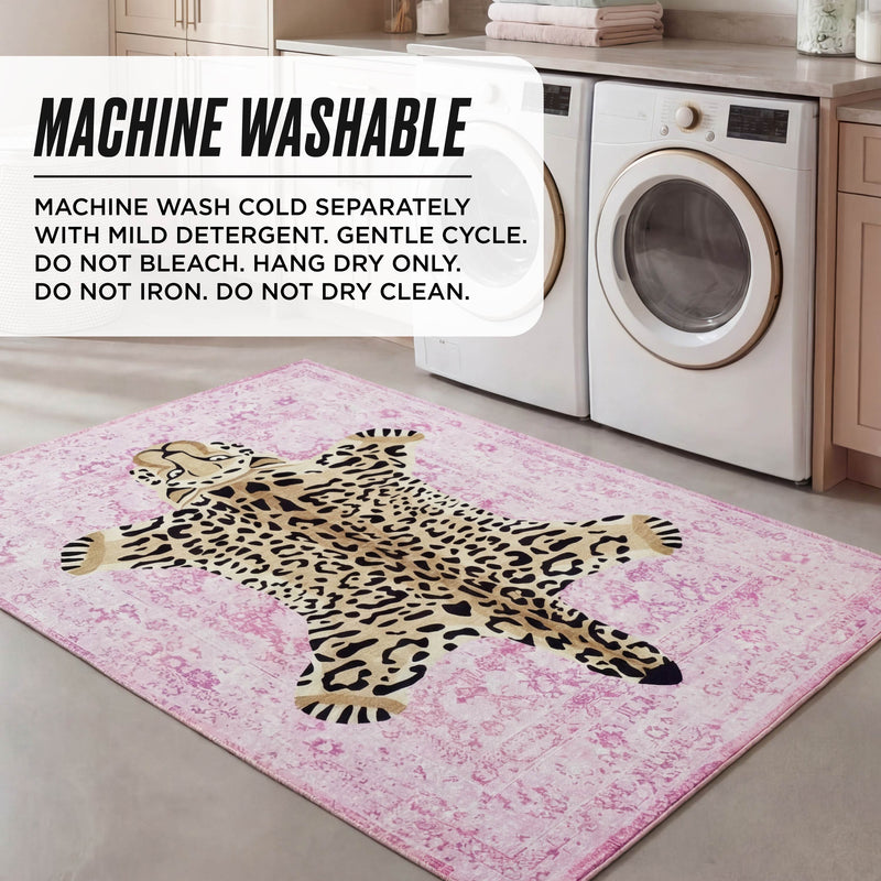 A laundry room with a washer and dryer showcases the Finely Washable Rug, 5' x 7', in pink leopard print. Text overlay: Machine wash cold, gentle cycle, do not bleach, hang dry only—no ironing or dry cleaning.