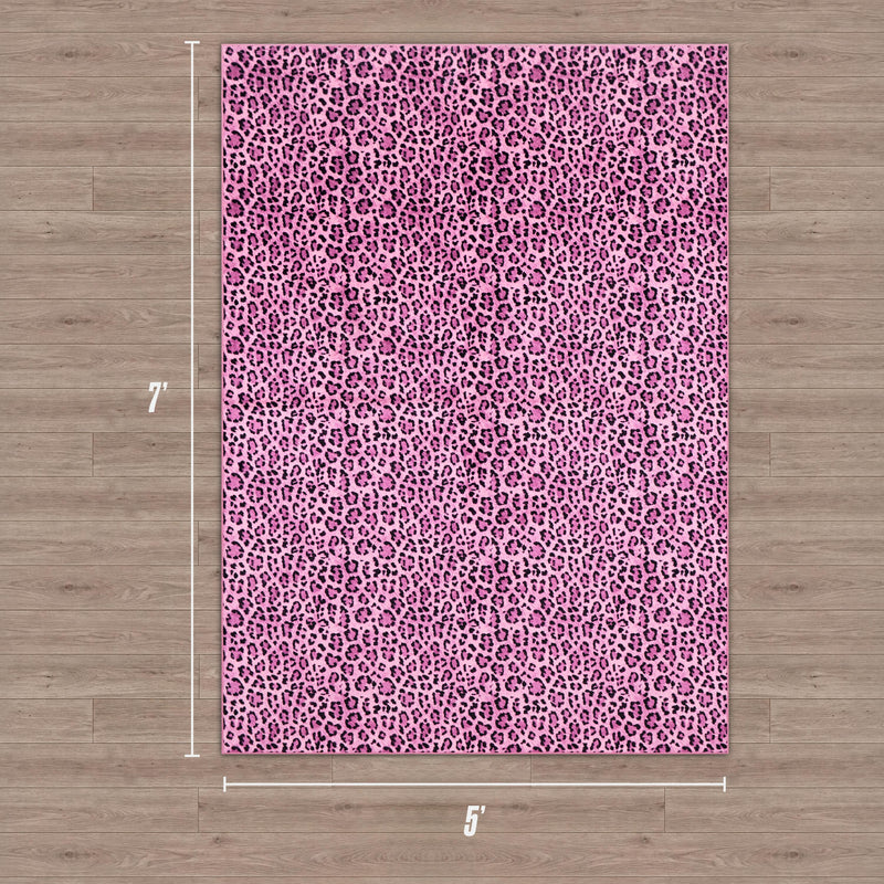 A Finely Washable Rug, 5' x 7', with a pink and purple leopard print, lies on a wood floor. The ultra-soft rectangular rug displays its dimensions clearly along the edges.