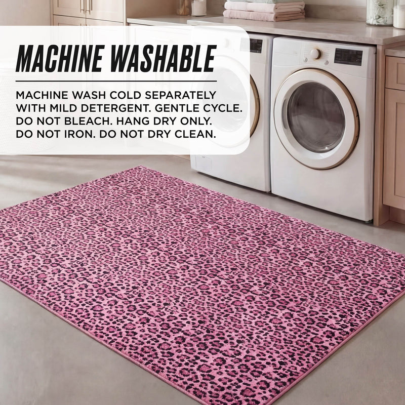 A Finely Washable Rug, 5' x 7', with pink leopard print, is placed in front of a washer and dryer. Text overlay: Machine washable. Wash cold separately with mild detergent, gentle cycle. Hang dry only.