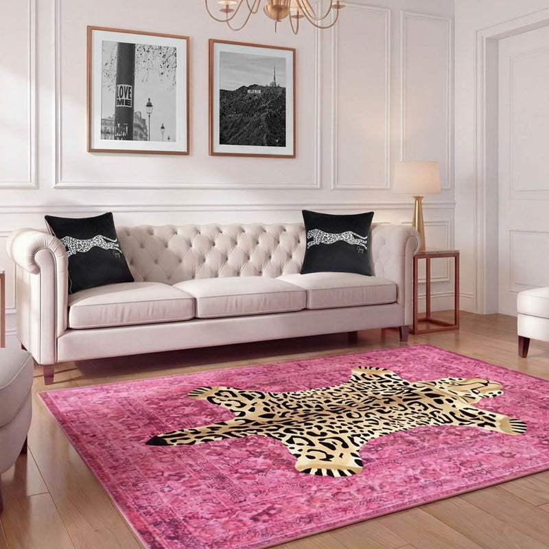 A stylish living room with a tufted cream sofa, black leopard-print pillows, and a Finely Washable Rug (7'10 x 10') featuring a leopard-print center. Three black-and-white framed photos hang on the white-paneled wall.