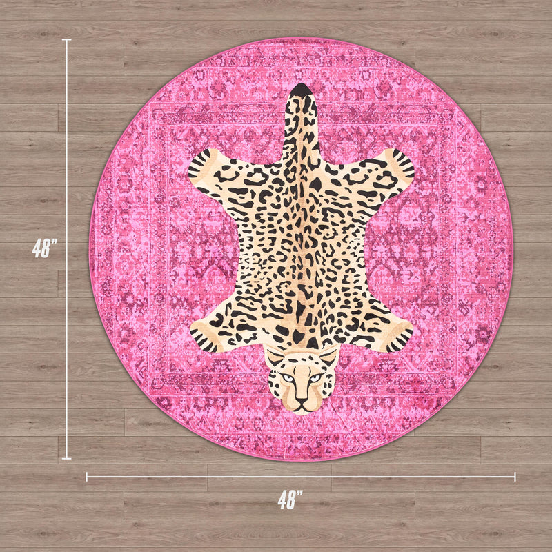 A round, pink Finely Washable Round Rug with a faux leopard print center. Ultra-soft and 48 inches wide, this chic rug is shown on a wood floor for a stylish touch.