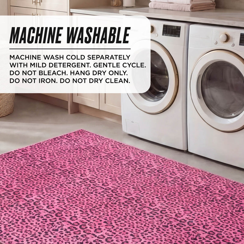 A laundry room showcases two white front-load washers and a Finely Washable Rug (7'10 x 10'), ultra-soft in pink leopard print. Sign: Machine washable. Wash cold separately, gentle cycle, mild detergent. Hang dry only. No bleach, iron, or dry clean.