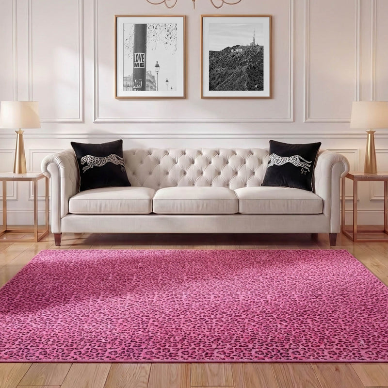 Elegant living room with a cream tufted sofa, two black pillows, glass side tables with lamps, and a bright pink Finely Washable Rug (7'10 x 10'). Two black-and-white framed photos hang on the white paneled wall.