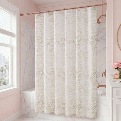 A bathroom with marble walls and a window features the Stassi Shower Curtain with PEVA Liner and Hooks 14-Piece Set in a stylish white and beige pattern, making a striking statement in the space. A vanity adorned with pink flowers in a vase and a round mirror on the right side enhances the elegant bath decor.