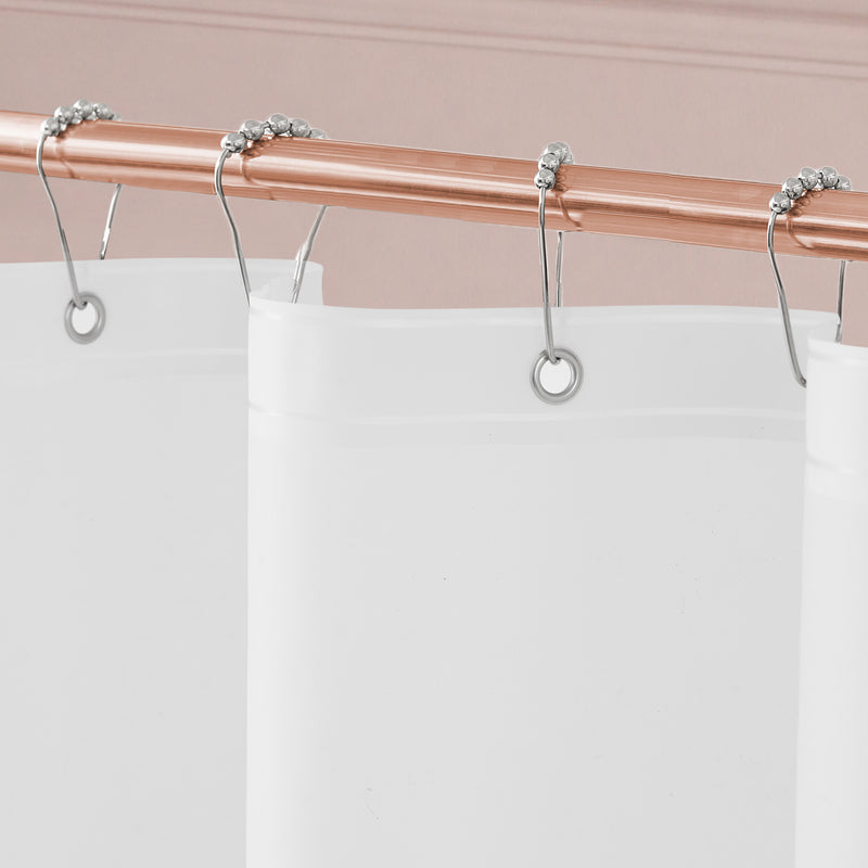 Close-up of the Stassi Shower Curtain with PEVA Liner and Hooks 14-Piece Set in white, hanging from silver hooks on a sleek copper shower rod against a pale pink wall—a chic addition that elevates your bath decor.