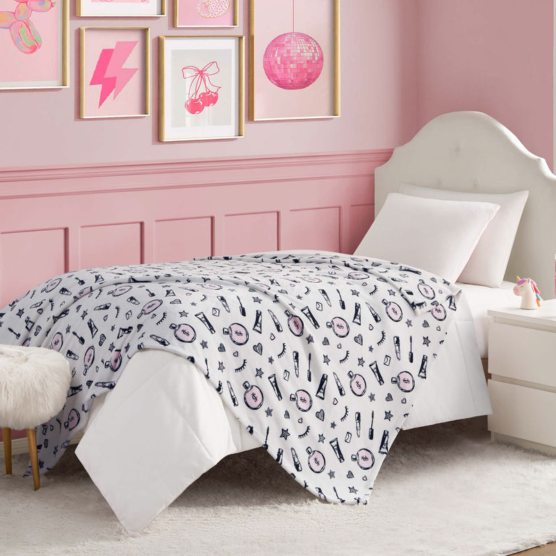 A neatly made bed with a white headboard and pink, white, and navy bedding brightens this pink-themed room. Wall art, a nightstand, and the Kids Plush Throw Blanket draped over a furry stool complete the cozy decor.