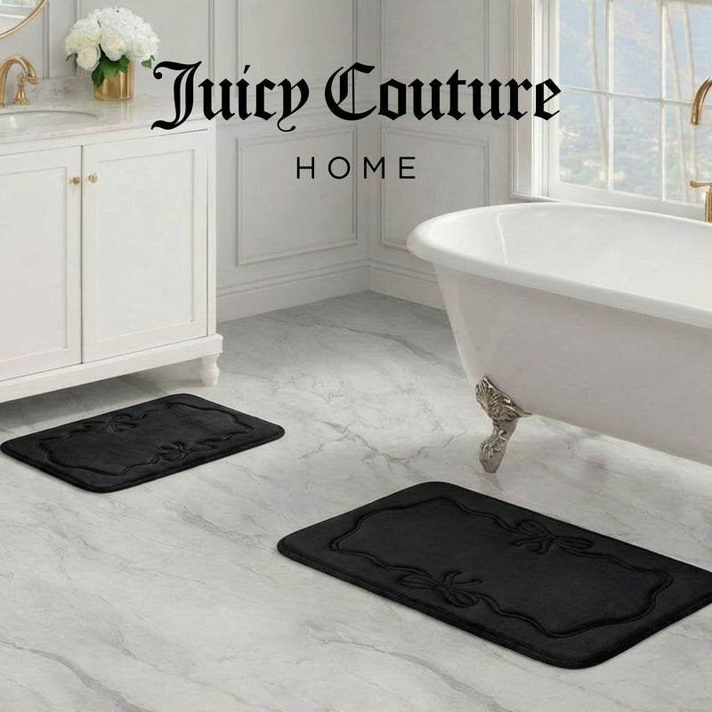 Elegant bathroom with white cabinets, clawfoot tub, marble floors, and two Quilted Memory Foam Bath Mats 2-Piece Set. "Juicy Couture Home" appears atop the image. A window and greenery bring charm to this serene space.