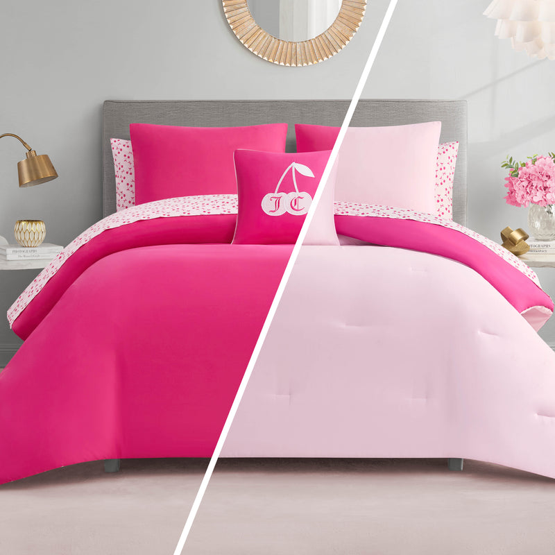 A bedroom features a bed split down the middle with the Cherry Reversible Bed in a Bag Bedding Set—bright pink on the left, light pink on the right. Decorative pillows, a gold lamp, flowers, and a round wall mirror complete the look.