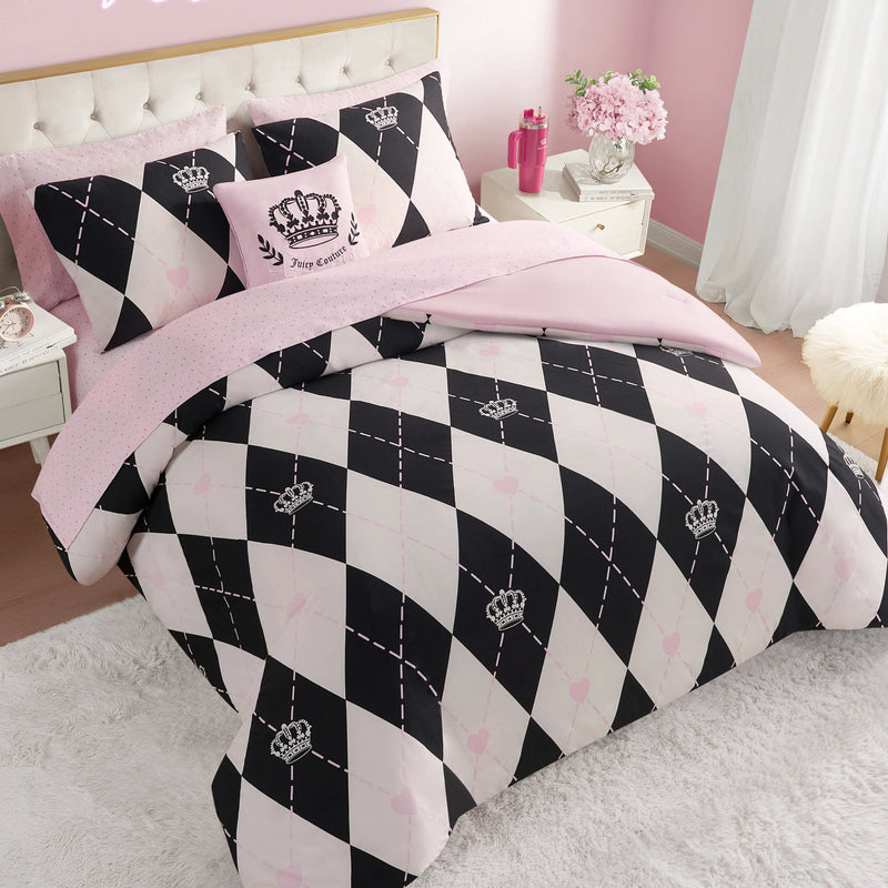 A neatly made bed features the Royal Argyle Reversible Bed in a Bag Bedding Set, with a black and white diamond pattern, crown motifs, and pale pink accents. Pink and white Juicy Couture pillows add a soft, feminine touch to this bright bedroom.