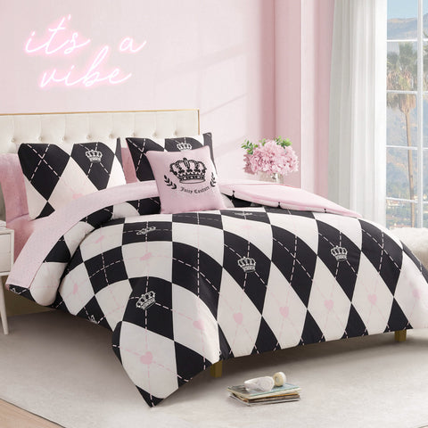 A stylish bedroom features the Royal Argyle Reversible Bed in a Bag Bedding Set with black and white argyle and crown motifs, pink accent pillows, pink walls, a neon "it's a vibe" sign, fresh flowers, and a window.