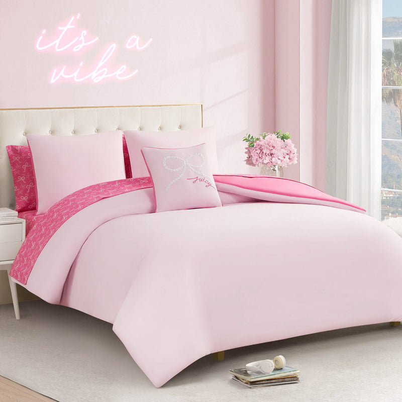 A neatly made bed with the Pearly Bows Reversible Bed in a Bag Bedding Set and a pink flower bouquet sits by a window. Above, a neon "it's a vibe" sign adds flair to this designer-inspired bedroom with soft pastel pink hues.