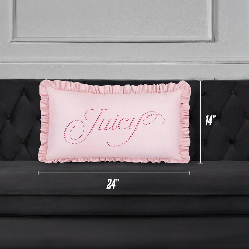 A Ruffle Decorative Pillow in pink with "Juicy" in cursive sparkles rests on a black tufted sofa. The pillow is 24"x14" and sits against a chic gray paneled wall for a stylish accent.