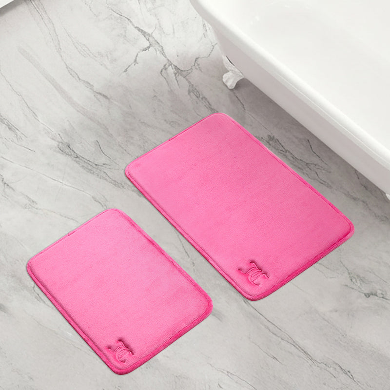 Two quilted memory foam bath mats from the 2-piece set are placed on a light gray marble bathroom floor next to a white bathtub.