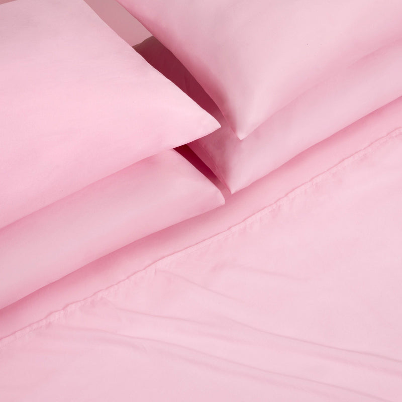 A close-up view of a neatly folded Microfiber Sheet Set With Extra Pillowcases, featuring pink bed sheets and pillowcases arranged on a matching pink bedspread, showcasing the essence of luxury bedding.