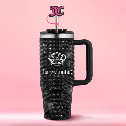 Introducing the Diamond Bling Stainless Steel Tumbler with Handle and Straw, 30 oz—a black tumbler adorned with sparkling rhinestones, featuring a crown logo and Juicy Couture text on the front. This stylish tumbler includes a metal straw topped with a pink JC charm and is showcased against a vibrant pink background.