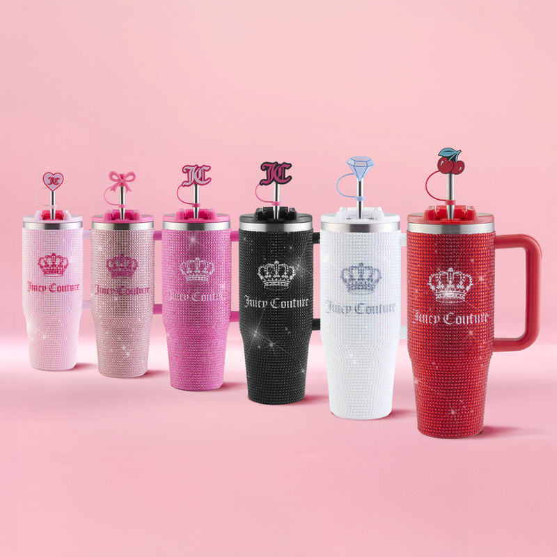 Six Diamond Bling Stainless Steel Tumblers with Handle and Straw, 30 oz, are arranged in a row on a pink surface. The collection showcases a gradient of colors from light pink to red, black, and white; each rhinestone tumbler comes with a uniquely decorated straw charm.