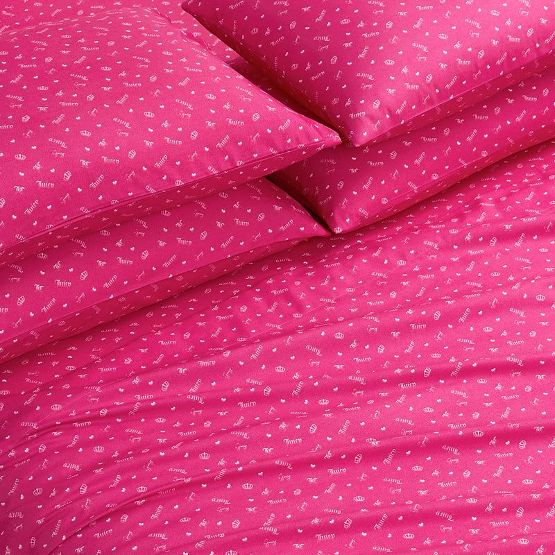 The Microfiber Sheet Set With Extra Pillowcases features bright pink bedding with playful white icons and words, arranged neatly on the bed. These ultra-soft sheets add a cheerful, inviting touch to any room.
