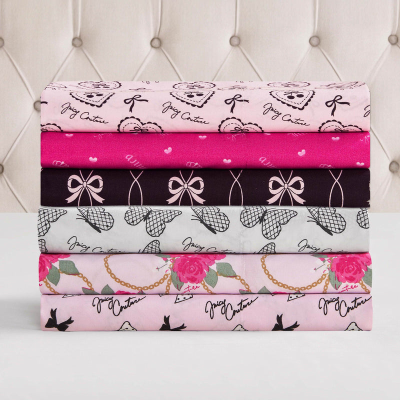 The Microfiber Sheet Set With Extra Pillowcases includes five ultra-soft sheets in pink, black, and white with bows, roses, hearts, gold chains, and script—perfect for bringing Juicy Couture bedding style to your space.