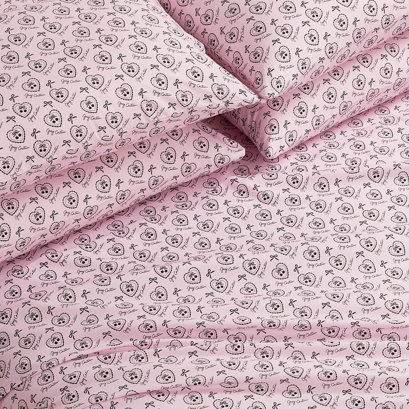 The Microfiber Sheet Set With Extra Pillowcases features a pink design with black outlined cartoon animal faces, bows, and decorative circles. This luxury bedding set looks soft, neatly arranged, and includes additional pillowcases.