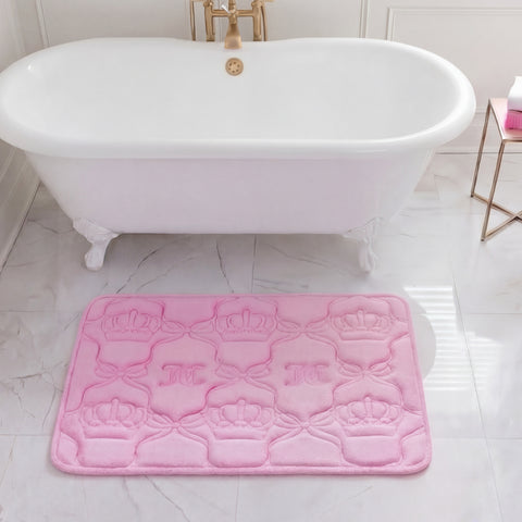 A white clawfoot bathtub sits in a marble-tiled bathroom with a plush Quilted Memory Foam Bath Mat (20" x 32") placed in front. A small gold side table nearby holds a white and pink bottle.