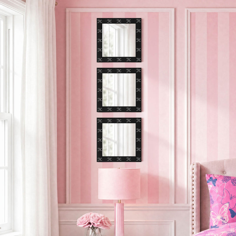 The Velour Rhinestone Logo 3-Piece Decorative Mirror Set features three square mirrors with black velour-look frames, arranged vertically on a pink striped wall above a pink lamp and flowers, beside a window with white curtains and a pale pink upholstered bed. This ready-to-hang set brings elegant charm to any space.