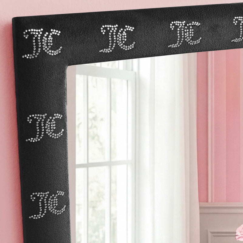 The Velour Rhinestone Logo 3-Piece Decorative Mirror Set features ready-to-hang black-framed mirrors adorned with JC initials in sparkling rhinestones. Standing against a pink wall, one mirror reflects a window draped in sheer white curtains, while the velour-look frames lend an elegant touch to this stylish décor set.