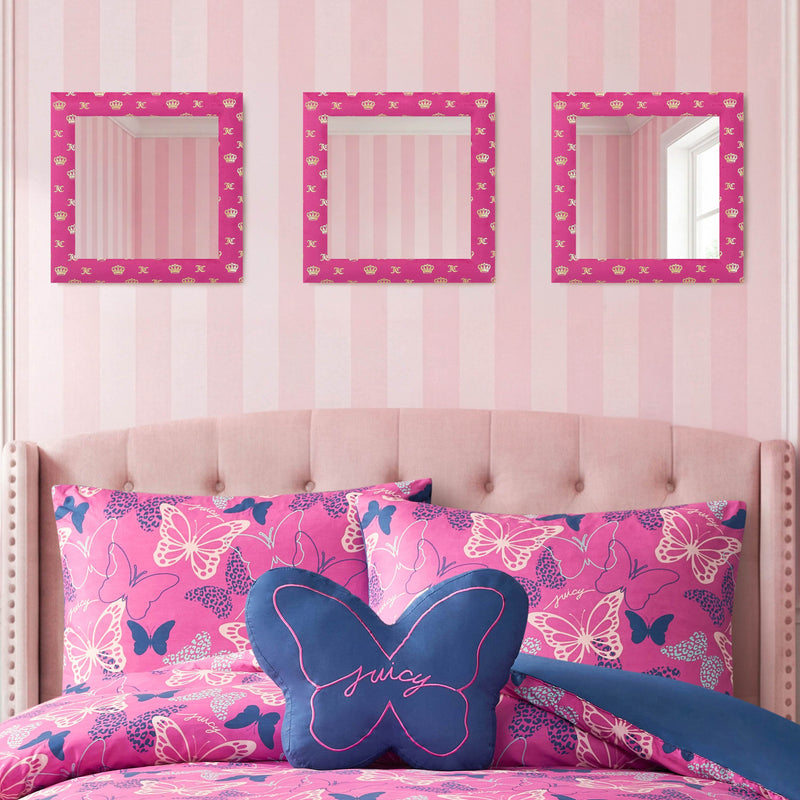 A pink and white striped wall is adorned with the Velour Crown Foil Print Hot Pink with Gold Foil 3-Piece 12 in x 12 in Decorative Mirror Set, ready to hang above a tufted pink headboard. The bed is styled with pink butterfly-patterned bedding and features a blue butterfly-shaped pillow embroidered with "Juicy.