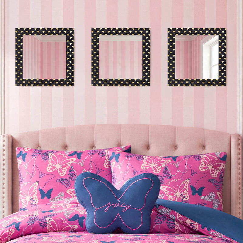 A pink bedroom featuring a tufted headboard, butterfly-patterned bedding, a blue butterfly-shaped Juicy pillow, and the Velour Heart Foil Print 3-Piece Decorative Mirror Set—with black heart-patterned velour-look frames—creates the perfect touch of charming wall décor against a pink striped wall.