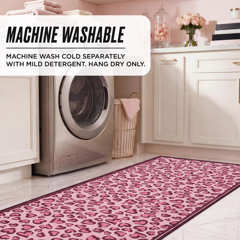 Finley Washable Rug, 2′ x 6′, a rectangular runner on a laundry room floor with a pink and dark red heart-print pattern and instructions to machine wash cold separately, mild detergent, and hang dry only.