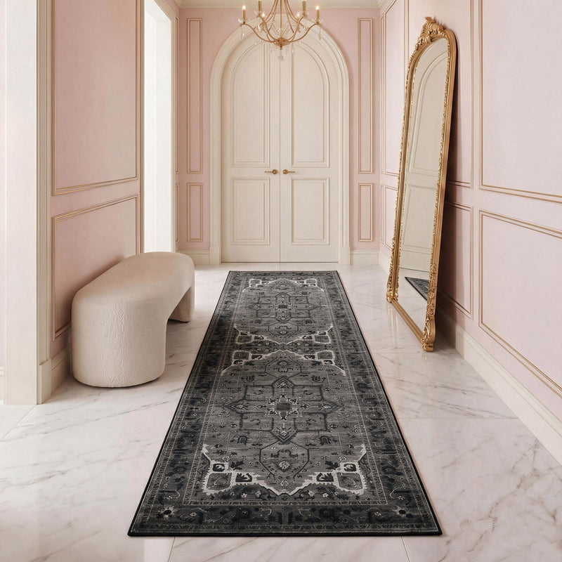 The Finley Washable Rug, 2′ x 6′, is a long, rectangular, ultra-soft runner rug with a dark grey, intricate traditional pattern centered in a hallway with white marble floors.