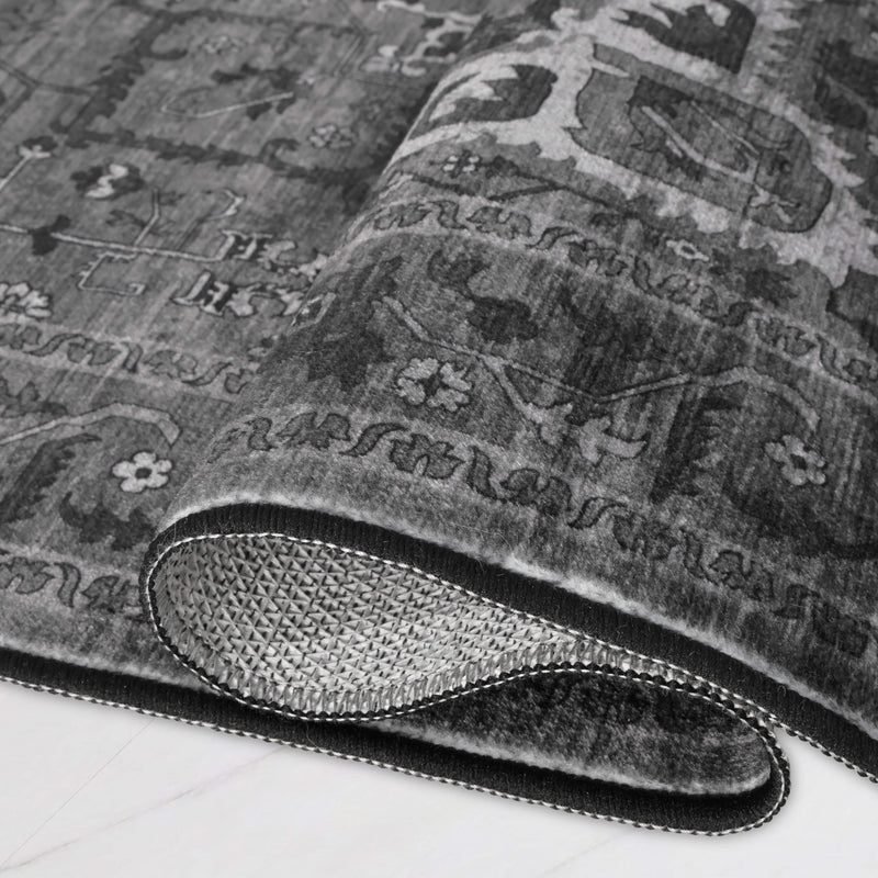 A rectangular, ultra-soft grey Finley Washable Rug, 2′ x 6′, with a traditional medallion pattern, shown partially rolled to reveal a non-slip backing.