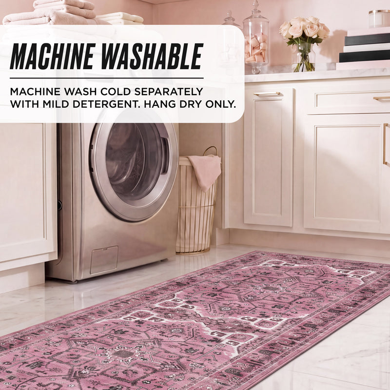 A rectangular pink patterned Finley Washable Rug, 2′ x 6′ on a laundry room floor in front of a washing machine, with text overlay reading: Machine washable. Machine wash cold separately with mild detergent. Hang dry only.