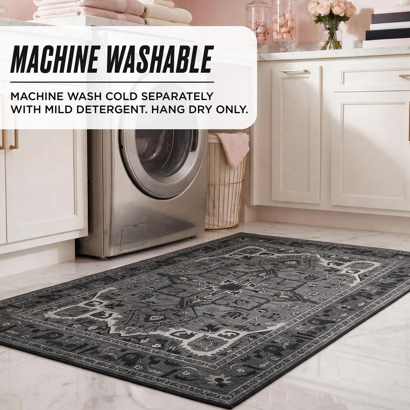 A dark gray patterned Finley Washable Rug, 5′ x 7′ on a kitchen floor, with text overlay: Machine wash cold separately with mild detergent. Hang dry only.