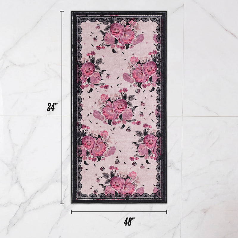 Finley Washable Rug, 2′ x 4′, an ultra-soft rectangular area rug with a pink floral pattern and a black decorative border.