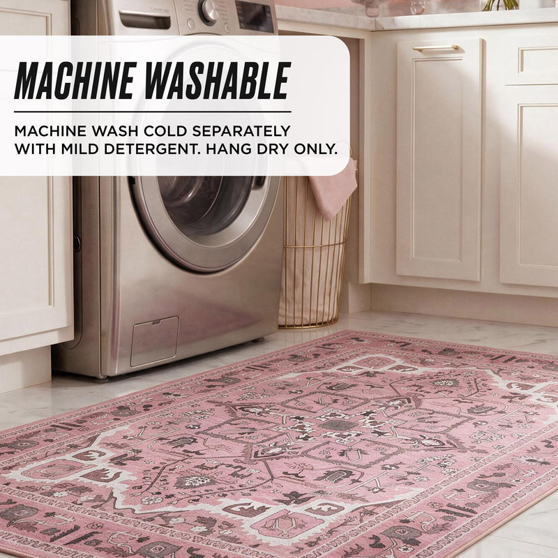 A vintage-style floral Finley Washable Rug, 8′ x 10′ lies on a kitchen floor in front of a washing machine, with text overlay detailing care instructions: MACHINE WASHABLE, MACHINE WASH COLD SEPARATELY, HANG DRY ONLY.