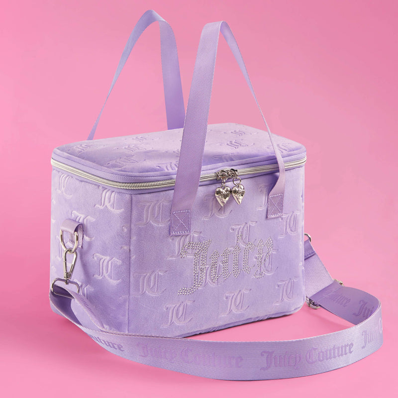 A lavender Chill Couture Cooler Bag by Juicy Couture with double handles, silver heart zipper pulls, and a detachable shoulder strap, set against a pink background. This stylish cooler bag features embossed logos and rhinestone Juicy lettering for a chic, playful look.