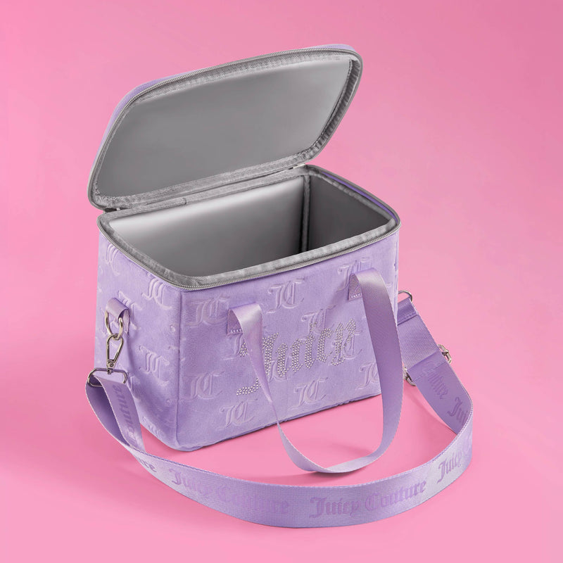 The Chill Couture Cooler Bag is a stylish Juicy Couture lunch tote in lavender, featuring an embossed logo pattern, a silver insulated interior, sparkling rhinestone “Juicy” text, and a matching adjustable strap—all beautifully showcased against a pink background.