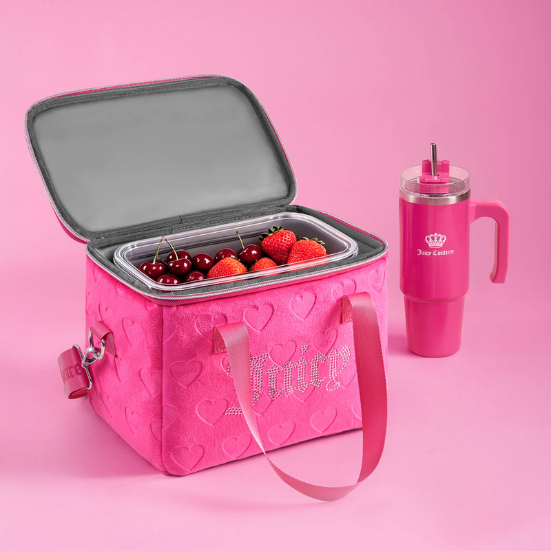 The Chill Couture Cooler Bag in pink, decorated with heart designs and filled with cherries and strawberries, sits next to a tall pink tumbler featuring a handle and straw.