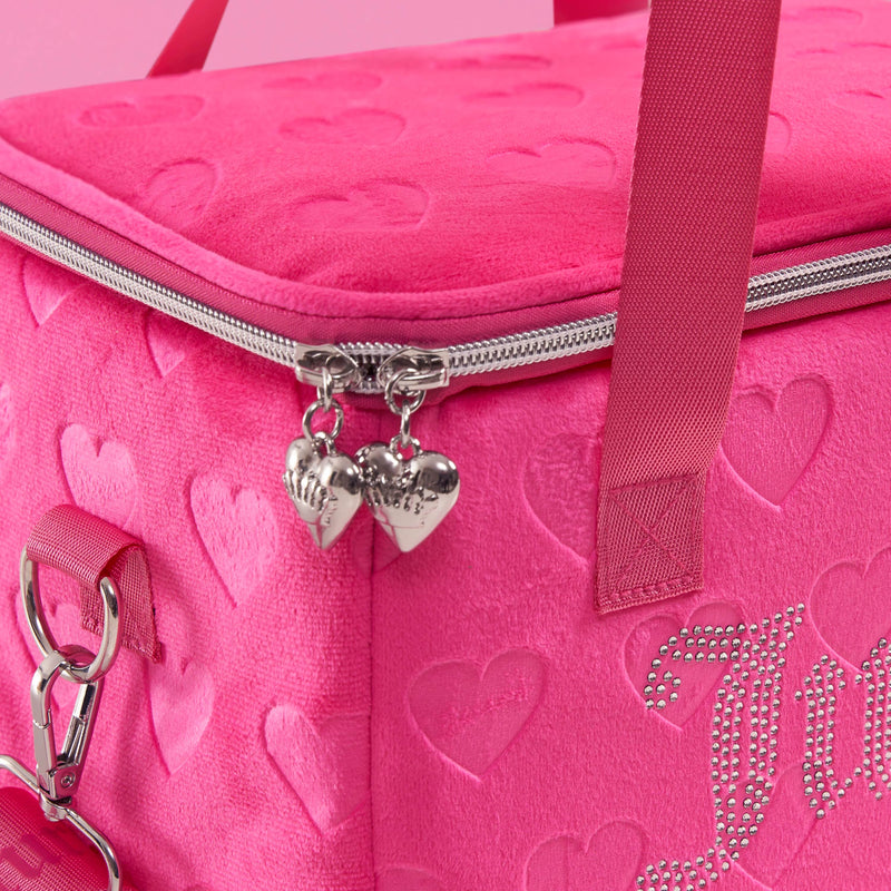 Close-up of a pink plush Chill Couture Cooler Bag featuring embossed heart patterns, jeweled Juicy Couture text, silver heart-shaped zipper pulls, and sturdy pink handles—a stylish cooler tote perfect for carrying your meals in fashion.